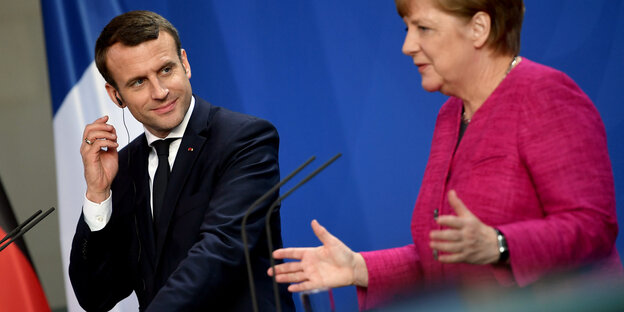Emmanuel Macron und Angela Merkel stehen vor Mikrofonen