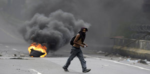 Ein junger Mann auf einer Straße vor einer brennenden Barrikade