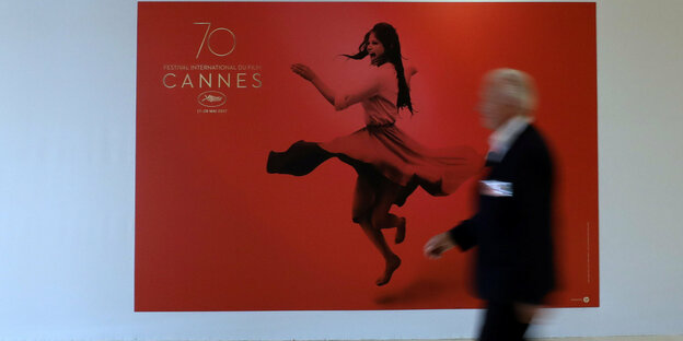 Ein Mann läuft an einem Plakat für die Festspiele von Cannes vorbei