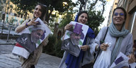 Iranische Frauen in grünen und violetten Gewändern breiten beide Arme aus und jubeln