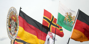 Sächsische Landesflagge, Deutschlandfahne, Fahne mit nationalistischer Symbolik und Anti-Merkel-Plakat