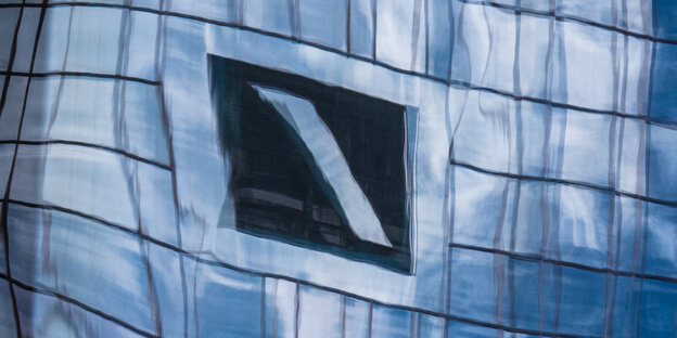 Ein Kasten mit Querstrich, das Emblem der Deutschen Bank, spiegelt sich in Fensterscheiben.
