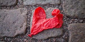 Ein zerplatzter roter Luftballon in Herzform liegt auf dem Boden