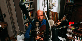 Bonnie „Prince“ Billy sitzt hinter Mikrofonen und spielt Guitarre