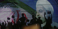 Jubelnde Iraner stehen vor einem Wandbild Hassan Rohanis