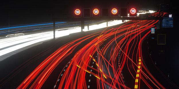 Langzeitbelichtung zeigt rote Leuchtspuren von PKW und LKW auf der Autobahn