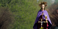 Eine Jesusstatue in lila Umhang vor Bäumen