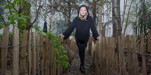 Inga Humpe steht in einem Hinterhofgarten und stützt sich auf einen niedrigen Zaun.
