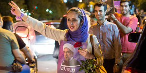 Eine Frau mit einem Plakat auf dem Ruhani abgebildet ist