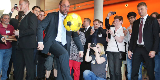 Martin Schulz kickt einen gelben Fußball mit dem Knie in die Luft
