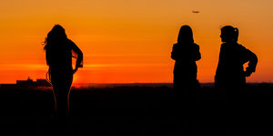 Silhouetten von drei Mädchen im Sonnenuntergang