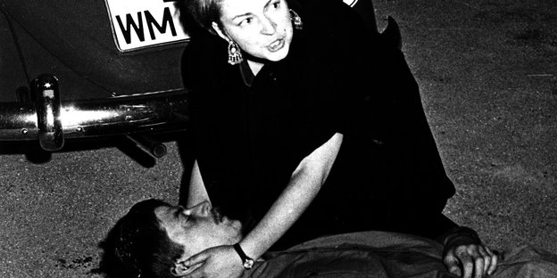 Friederike Hausmann beugt sich über den erschossenen Benno Ohnesorg und hält seinen Kopf. Im Hintergrund steht ein Auto