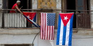 Ein Mann hängt US-amerikanische und kubanische Flaggen an einem Haus in Havana