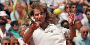 Ein junger Mann mit langen Haaren mit einem Tennisschläger