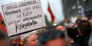 Köpfe auf einer Demo. In Mitten der Menge ein Schild: 