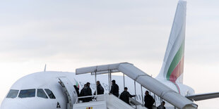 Menschen gehen über eine offene Gangway in ein Flugzeug