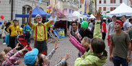 Ein Clownsperformance auf einem Marktplatz. Kinder schauen zu