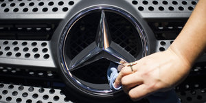 Hand putzt einen Mercedes-Stern an einem Fahrzeug