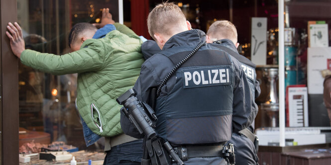 Zwei Polizisten durchsuchen einen Mann