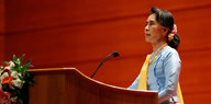 Aung San Suu Kyi steht an einem Rednerpult