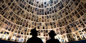 Zwei Männer stehen in der "Halle der Namen" in Yad Vashem, in der die Gesichter der ermordeten Juden bis in den Himmel reichen