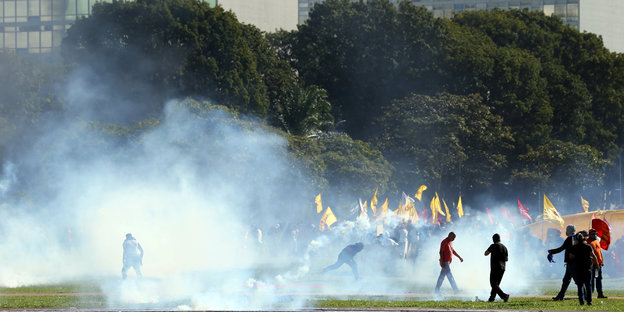 Menschen mit Fahnen und Tränengas