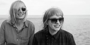 Ein schwarz-weiß Foto, auf dem zwei Frauen mit Sonnenbrillen zu sehen sind
