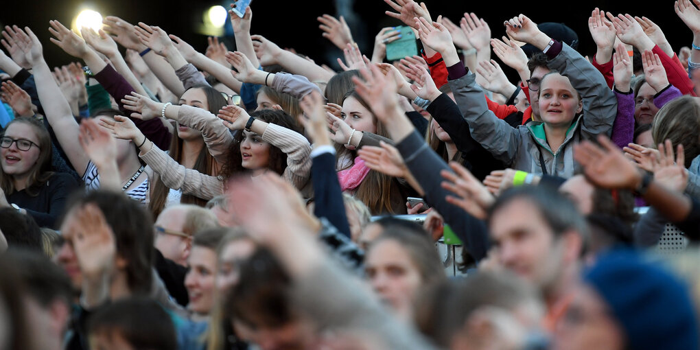 Junge Menschen recken ihre Arme in die Luft