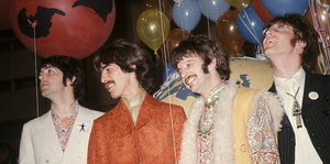 Vier Männer, The Beatles, hinter ihnen Luftballons
