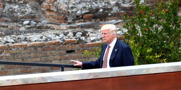Trump im Halbprofil vor einer alten Mauer