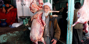Ein afghanischer Metzger trägt ein geschlachtetes Schaf über seiner Schulter