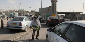 ein Mann auf einer Straße, im Hintergrund Grenzanlagen