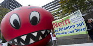 Eine aufblasbare Riesentomate auf einer Demonstration, daneben Transparent gegen Patente auf Saatgut.