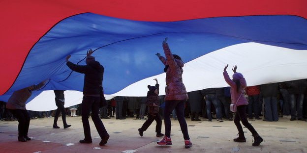 Kinder laufen unter einer großen Russland-Fahne