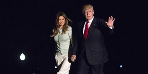 Trump schreitet, seine Frau Melania an der Hand, forsch durch die Dunkelheit und winkt