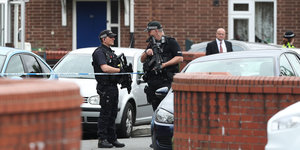 Zwei bewaffnete Polizisten stehen vor einem Haus