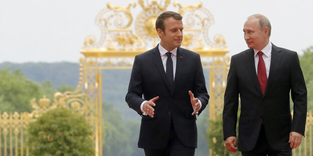 Emmanuel Macron und Vladimir Putin laufen nebeneinander