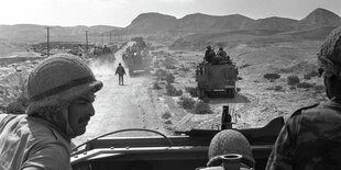 Soldaten sitzen in einem Auto, hinter ihnen eine Bergkette