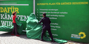 Katrin Göring-Eckardt und Cem Özdemir enthüllen eine grüne Werbetafel, die den Zehn-Punkt-Plan wiedergibt