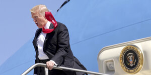 Trump, dessen Krawatte von einem Windstoß hochgewirbelt wird
