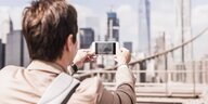 Ein junger Mann fotografiert mit seinem Handy die Skyline von New York