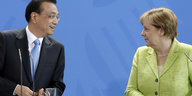 Li und Merkel schauen sich an, vor einem blauen Hintergrund mit Bundesadler
