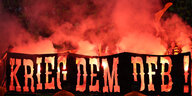 Im Hintergrund roter Rauch und Flammen, im Vordergrund der Schriftzug "Krieg dem DFB"
