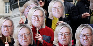 Aktivisten halten sich Masken vors Gesicht, die das Gesicht von Jean-Marie Le Pen mit den Haaren seiner Tochter Marine Le Pen zeigen