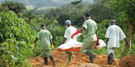 Mitglieder des Roten Kreuzes von Guinea tragen einen mit Ebola infizierten Leichnam über den Friedhof von Gueckedou, Guinea