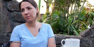 Eine Frau sitzt mit einer Kaffeetasse am Tisch Eine Frau sitzt mit einer Kaffeetasse am Tisch