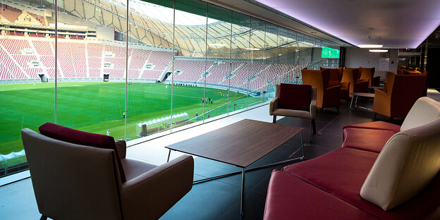 VIP-Lounge mit Sesseln in einem Fußballstadion - mit Blick durchs Fenster ins Stadionrund