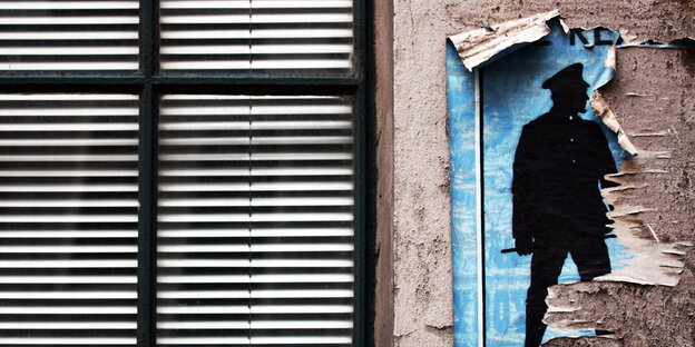 Ein halb abgerissenes Plakat von einem stilisierten Polizisten hängt an einer Hauswand