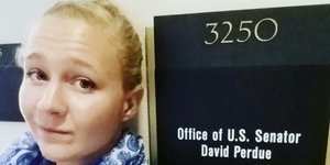 Eine blonde Frau vor dem Büroschild eines US-Senators