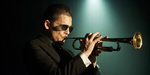 Foto zeigt den Schauspieler Ethan Hawke als Chet Baker, der eine Sonnenbrille trägt und Trompete spielt